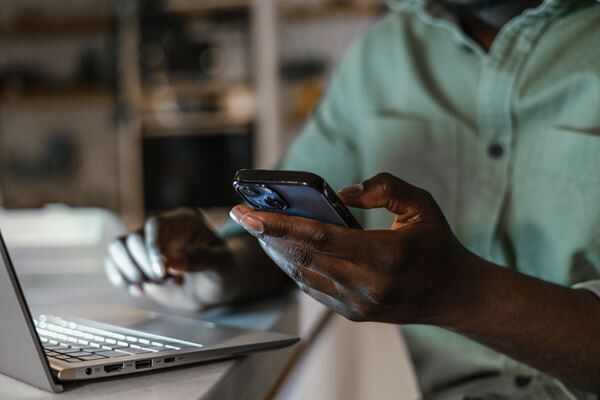 person typing on computer and using phone