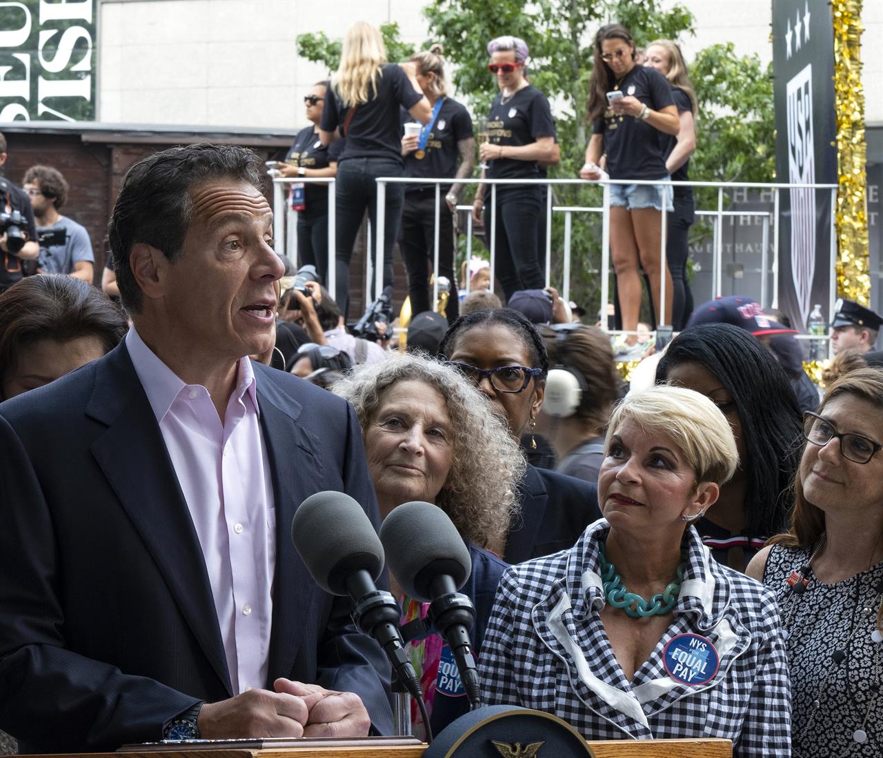 With members of the U.S. women's soccer team in the background before the start of a ticker tape parade in their honor, Gov. Andrew Cuomo speaks before signing a bill into law Wednesday, July 10, 2019, in New York. The bill will expand a law banning gender pay discrimination to make it illegal for employers to pay workers differently based on their age, race, religion or other characteristics, and making it easier for workers to prove pay discrimination in court. (AP Photo/Craig Ruttle)
NY expands pay equity law on day honoring US soccer team