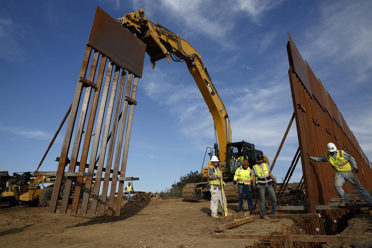 FILE - In this Jan. 9, 2019 file photo, construction crews install new border wall sections seen from Tijuana, Mexico. What started as an online fundraiser to provide President Donald Trump with donations for his southern border wall has morphed into a new foundation whose members vow to build a wall themselves. The "We The People Will Build the Wall" campaign has surpassed $20 million since it was created in December by Air Force veteran and triple amputee Brian Kolfage. (AP Photo/Gregory Bull, File)