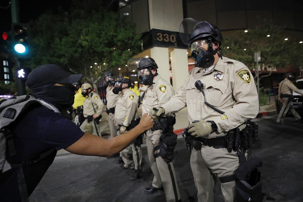 A protester bumps fists with a police officer at a rally Monday, June 1, 2020, in Las Vegas, over the death of George Floyd, a black man who had been detained by police in Minneapolis. (AP Photo/John Locher)
2 Las Vegas shootings, 1 officer shot amid Floyd protests