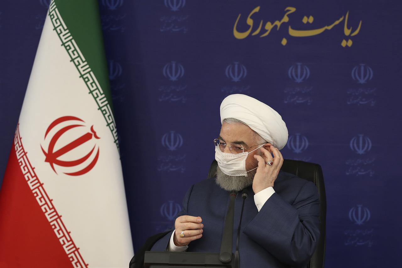 FILE - In this July 18, 2020 file photo, released by the official website of the office of the Iranian Presidency, President Hassan Rouhani adjusts his face mask in a meeting of the national headquarters of the fight against the COVID-19, in Tehran, Iran. Iranian hard-liners in parliament voted Wednesday, Aug. 12, 2020, against Rouhani’s nominee for trade minister. The vote marked the first serious confrontation between the newly elected house, dominated by conservatives and the bloc of supporters of the relatively moderate Rouhani. Writing in Farsi reads: "The Presidency." (Iranian Presidency Office via AP, File)
