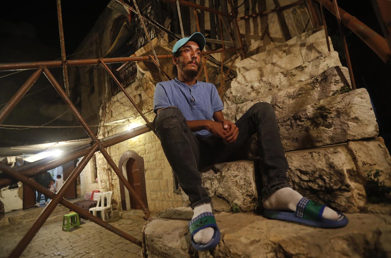 Lebanese Mohammed Sufian, 21, sits outside his house, in Tripoli, north Lebanon Thursday, Sept. 17, 2020, days after he was rescued at sea by a U.N. naval force after trying to migrate with his family on a boat to Cyprus. He ended up losing his two-year-old son as a result of severe heat with no food or water on board. Mohammed is among dozens of people who have tried in recent weeks to flee Lebanon to Europe amid a devastating and unprecedented economic and financial crisis. (AP Photo/Hussein Malla)