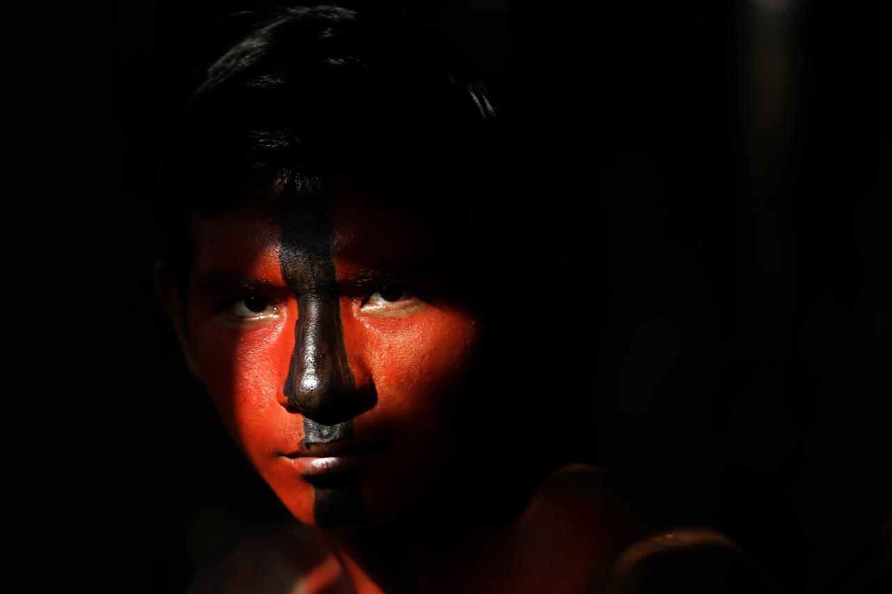 Tenetehara Indigenous Jair Tembe eyes the camera during a festival at the Alto Rio Guama Indigenous Territory, near Paragominas, in the Brazilian state of Para, Brazil, Monday, Sept. 7, 2020. The Indigenous group, also known as Tembe, held a festival during the week to celebrate and give thanks that none of their members have fallen ill during the new coronavirus pandemic, after closing their area off in March. (AP Photo/Eraldo Peres)