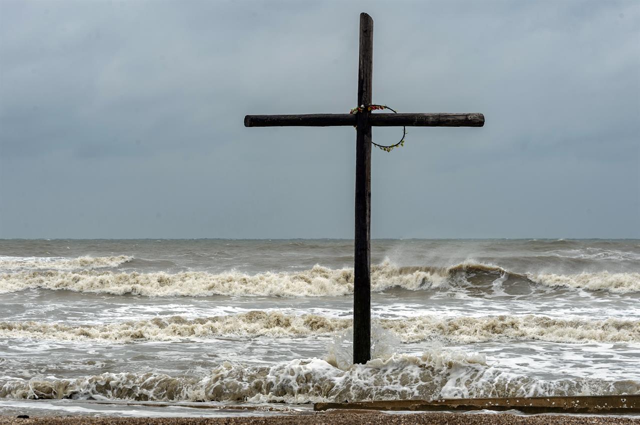 The cross that stands on the beach near the intersection of Highway 124 and Highway 87 gets buffeted by the high seas on Bolivar Peninsula, Texas, Sunday, Sept. 20, 2020. Tropical Storm Beta was expected this week to bring heavy rainfall to parts of the upper Texas Gulf Coast and Louisiana, adding to the stress and worry residents and officials have already dealt with during a busy hurricane season. (Fran Ruchalski/The Beaumont Enterprise via AP)