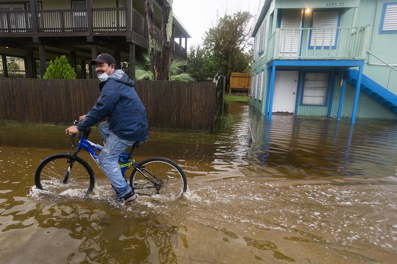 Rafael Juarez rides his bicycle through a street flooded by Tropical Storm Beta as he makes his way home from the store Monday, Sept. 21, 2020, in Galveston, Texas. (Brett Coomer/Houston Chronicle via AP)