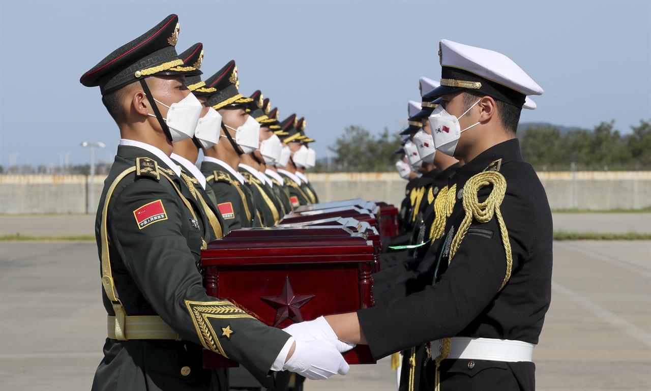 In this photo provided by the South Korea Defense Ministry, Chinese honor guard members, left, receive caskets containing the remains of Chinese soldiers from South Korean honor guards during the handing over ceremony at the Incheon International Airport in Incheon, South Korea, Sunday, Sept. 27, 2020. The remains of 117 Chinese soldiers who died in the 1950-53 Korean War were returned to China on Sunday in an annual repatriation delayed this year by the coronavirus outbreak. (South Korea Defense Ministry via AP)