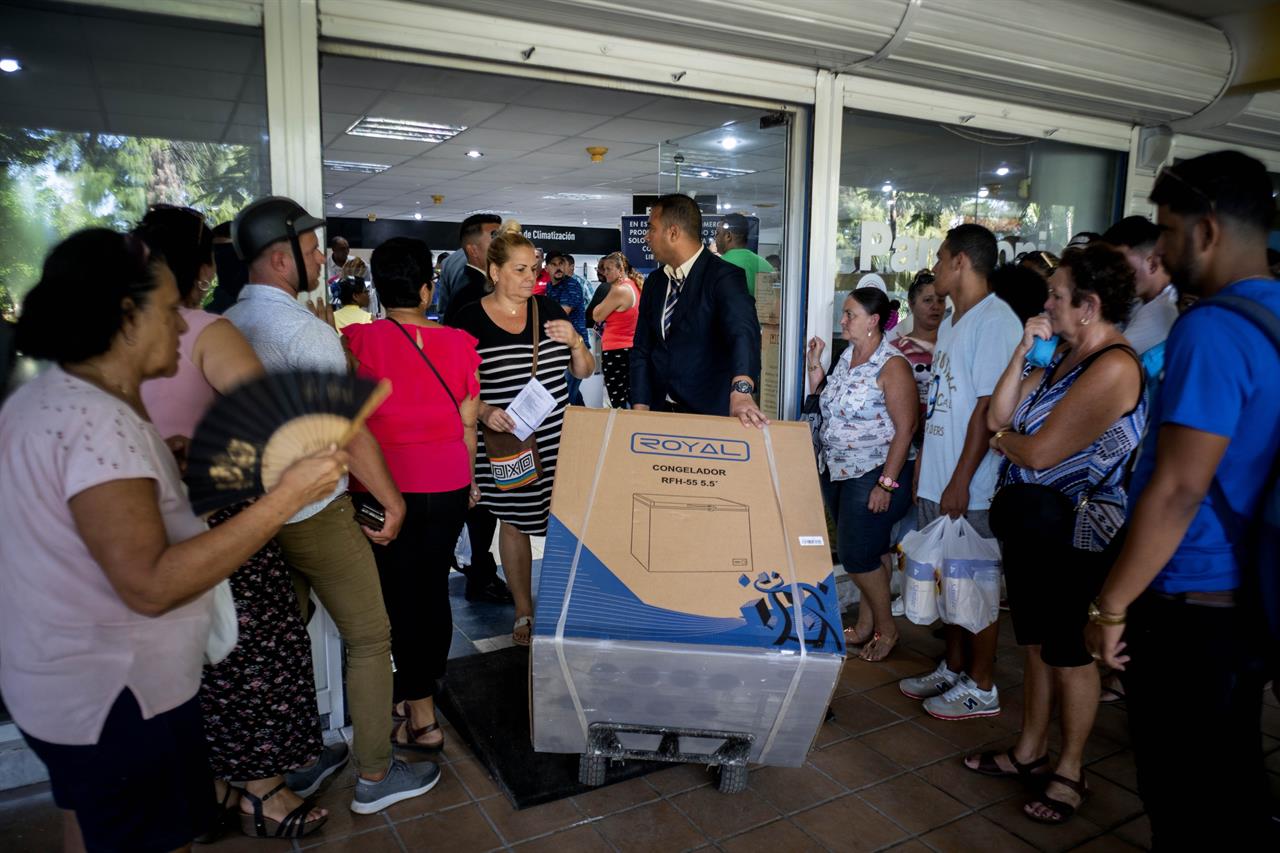 FILE - In this Oct 28, 2019 file photo, a worker wheels out a newly purchased freezer for a customer at a "dollar store" as shoppers wait to enter, in Havana, Cuba. A debit card backed by remittances that recently became popular in Cuba because people can use it to buy home appliances, food, and replacement parts has landed on the U.S. government’s restricted list, as of Monday, Sept. 28, 2020, in a statement by U.S. Secretary of State Mike Pompeo. (AP Photo/Ramon Espinosa, File)