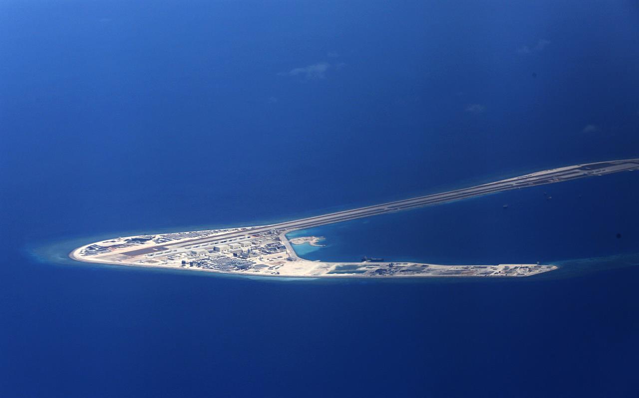 FILE - In this April 21, 2017, file photo, Chinese structures and an airstrip on the man-made Subi Reef at the Spratlys group of islands are seen from a Philippine Air Force C-130 transport plane off the disputed South China Sea in western Philippines. U.S.-China friction has flared again, with Beijing firing back at accusations by Washington that it is a leading cause of global environmental damage and has reneged on its promise not to militarize the South China Sea. (Francis Malasig/Pool Photo via AP, File)