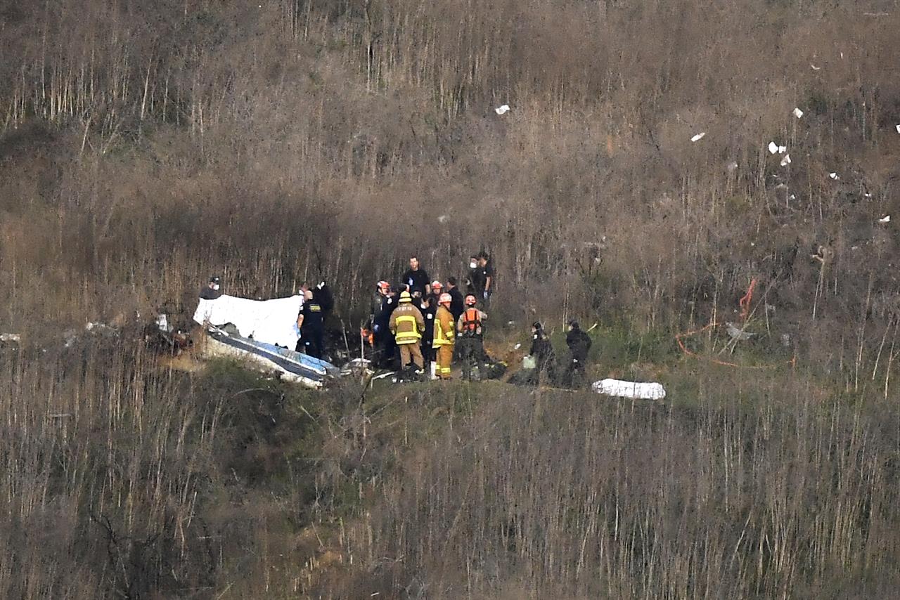 FILE - In this Jan. 26, 2020, file photo, a body is covered, left, while another is seen at right at the scene of a helicopter crash that killed former NBA basketball player Kobe Bryant and eight others in Calabasas, Calif. Gov. Gavin Newsom has approved legislation prompted by the helicopter crash that killed Kobe Bryant and eight others. The bill he signed Monday, Sept. 28, 2020, makes it a crime for first responders to take unauthorized photos of deceased people at the scene of an accident or crime. (AP Photo/Mark J. Terrill, File)