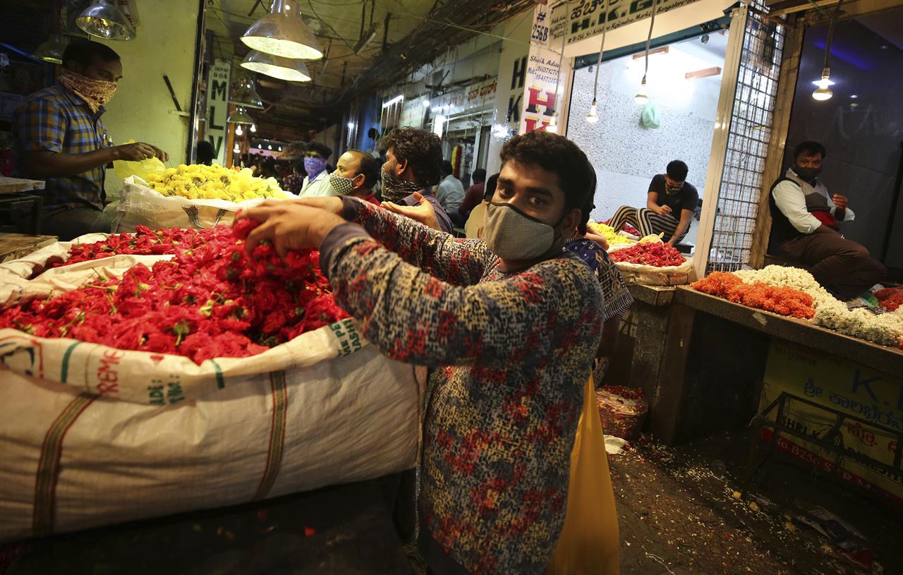 Vendors arrange flowers at a wholesale flower market ahead of the Hindu festival of Dussehra, in Bengaluru, India, Friday, Oct. 23, 2020. Health officials have warned about the potential for the coronavirus to spread during the upcoming religious festival season, which is marked by huge gatherings in temples and shopping districts. (AP Photo/Aijaz Rahi)
