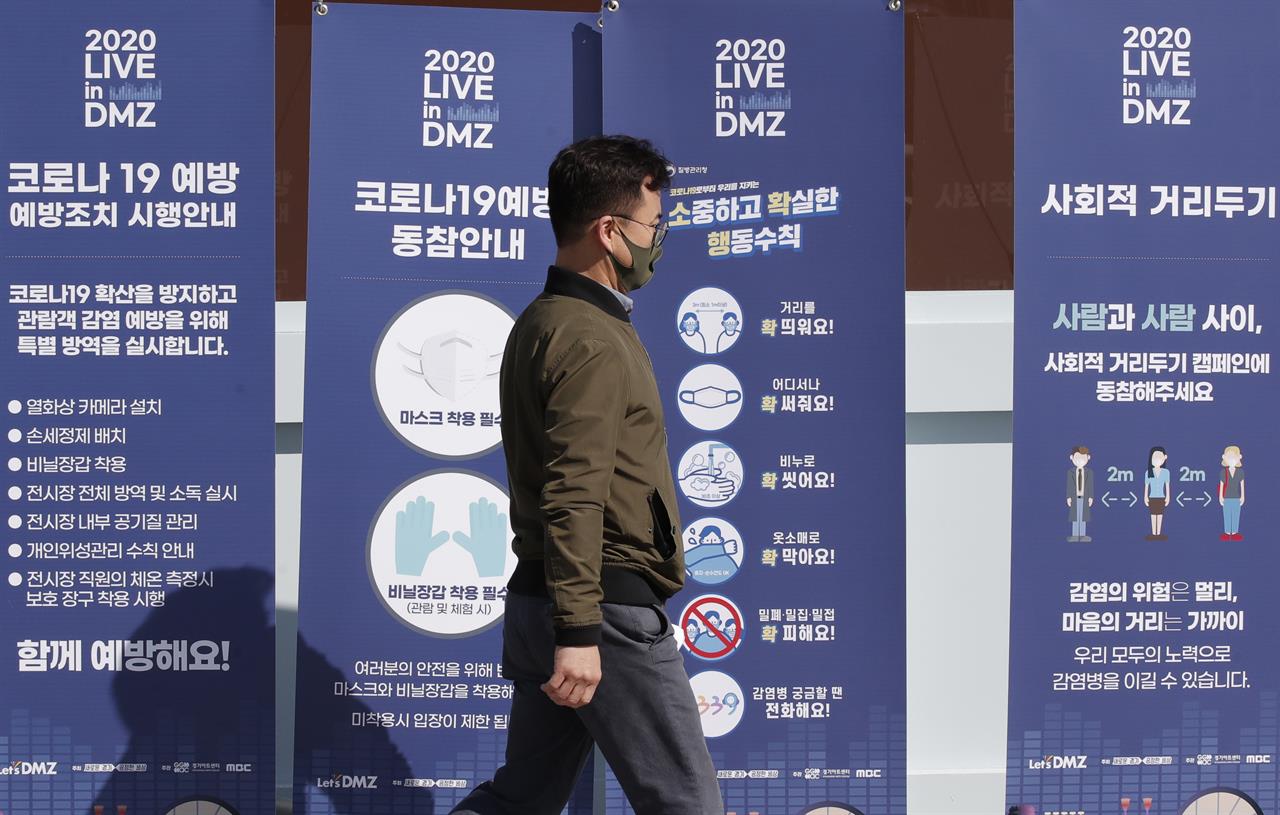 A man wearing a face mask walks past near banners showing precaution against the coronavirus, at the Imjingak Pavilion in Paju, South Korea, Friday, Oct. 23, 2020. South Korea recorded its highest increase in coronavirus cases in more than 40 days on Friday as more infections were reported at hospitals and nursing homes. (AP Photo/Lee Jin-man)
