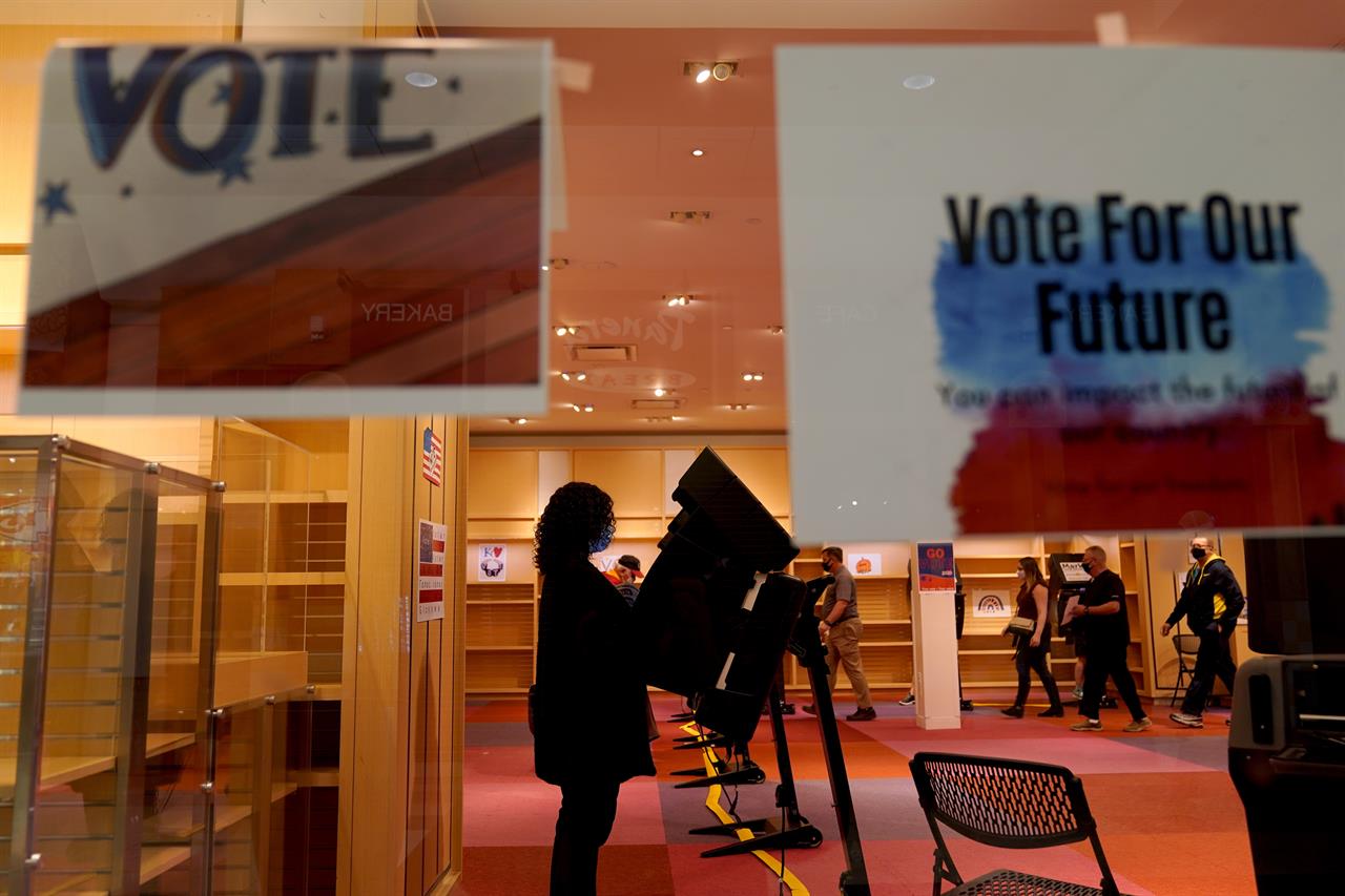 FILE - In this Oct. 17, 2020, file photo, a woman casts her ballot on the first day of early voting in a recently-shuttered store at Oak Park Mall in Overland Park, Kan. As it has for more than 170 years, The Associated Press will count the vote and report the results of presidential, congressional and state elections quickly, accurately and without fear or favor on Nov. 3 and beyond. (AP Photo/Charlie Riedel, File)