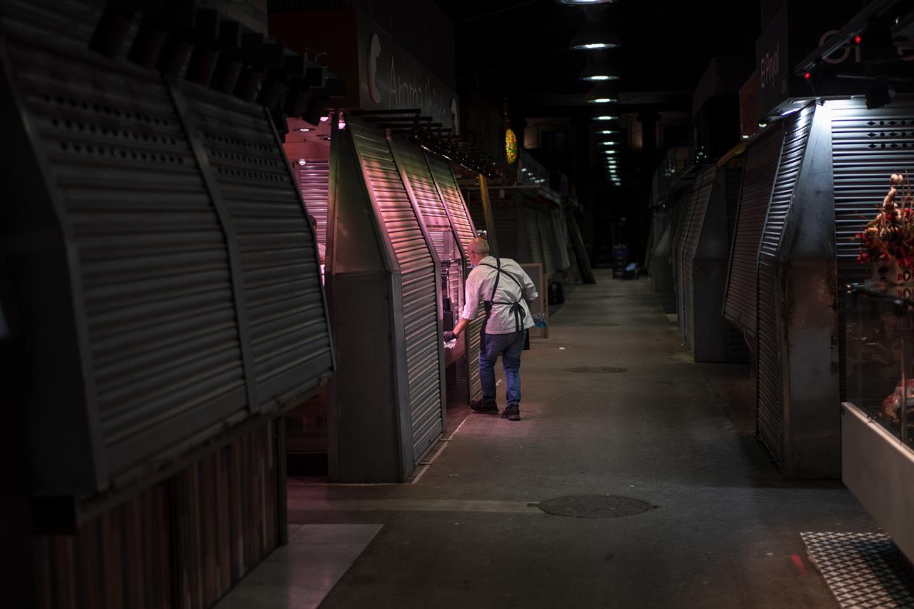 A vendor closes his cured ham shop in a market in Barcelona, Spain, Friday, Oct. 23, 2020. (AP Photo/Emilio Morenatti)