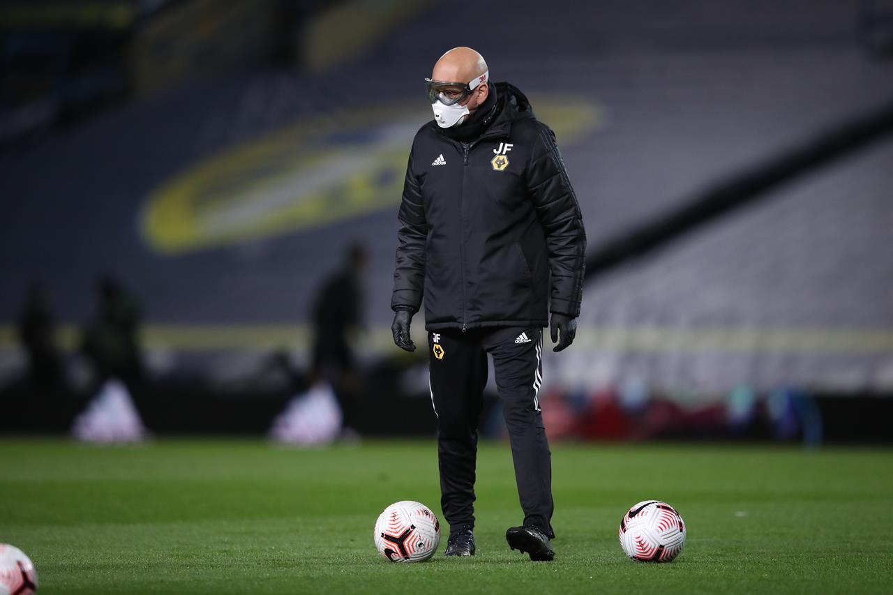 A Leeds United's assistant coach, name not available, wearing protective goggles and a mask, to help prevent the spread of coronavirus, helps players to warm up prior to the English Premier League soccer match between Leeds United and Wolverhampton Wanderers at Elland Road ground in Leeds, England, Monday, Oct. 19, 2020. (Martin Rickett/Pool via AP)