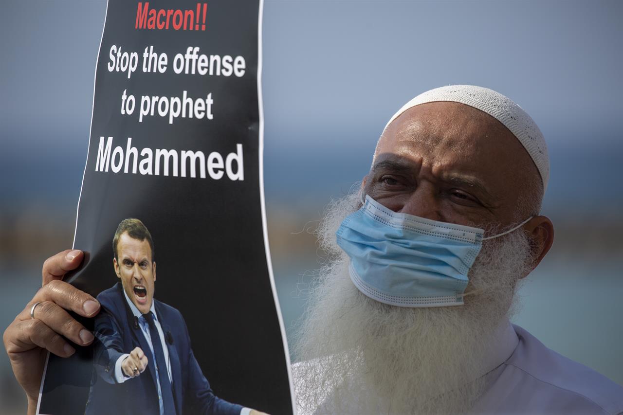 
              An Israeli Arab protester wearing a face mask due to the coronavirus pandemic holds a sign during a protest against French President Emmanuel Macron and the publishing of caricatures of the Muslim Prophet Muhammad they deem blasphemous, in front of the French embassy in Tel Aviv, Israel, Tuesday, Oct. 27, 2020. (AP Photo/Ariel Schalit)
            