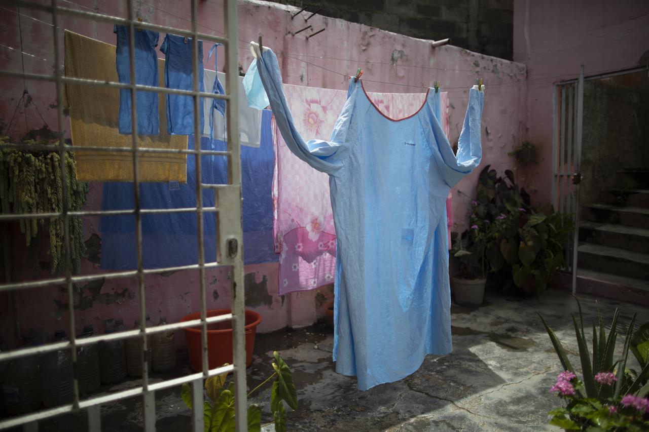 One of Elena's Suazo's two medical gowns hangs to dry at her parents' home in the Catia neighborhood of Caracas, Venezuela, Tuesday, Sept. 29, 2020, in between her twice-daily trips to care for her hospitalized father in the COVID-19 wing of the Jose Gregorio Hernandez public hospital. On a cafeteria worker's monthly salary, Suazo had no money to buy the needed protective gear, so her younger brother bought her one suit and her son's mother-in-law gave her a second, allowing her to attend him inside the hospital twice a day. (AP Photo/Ariana Cubillos)