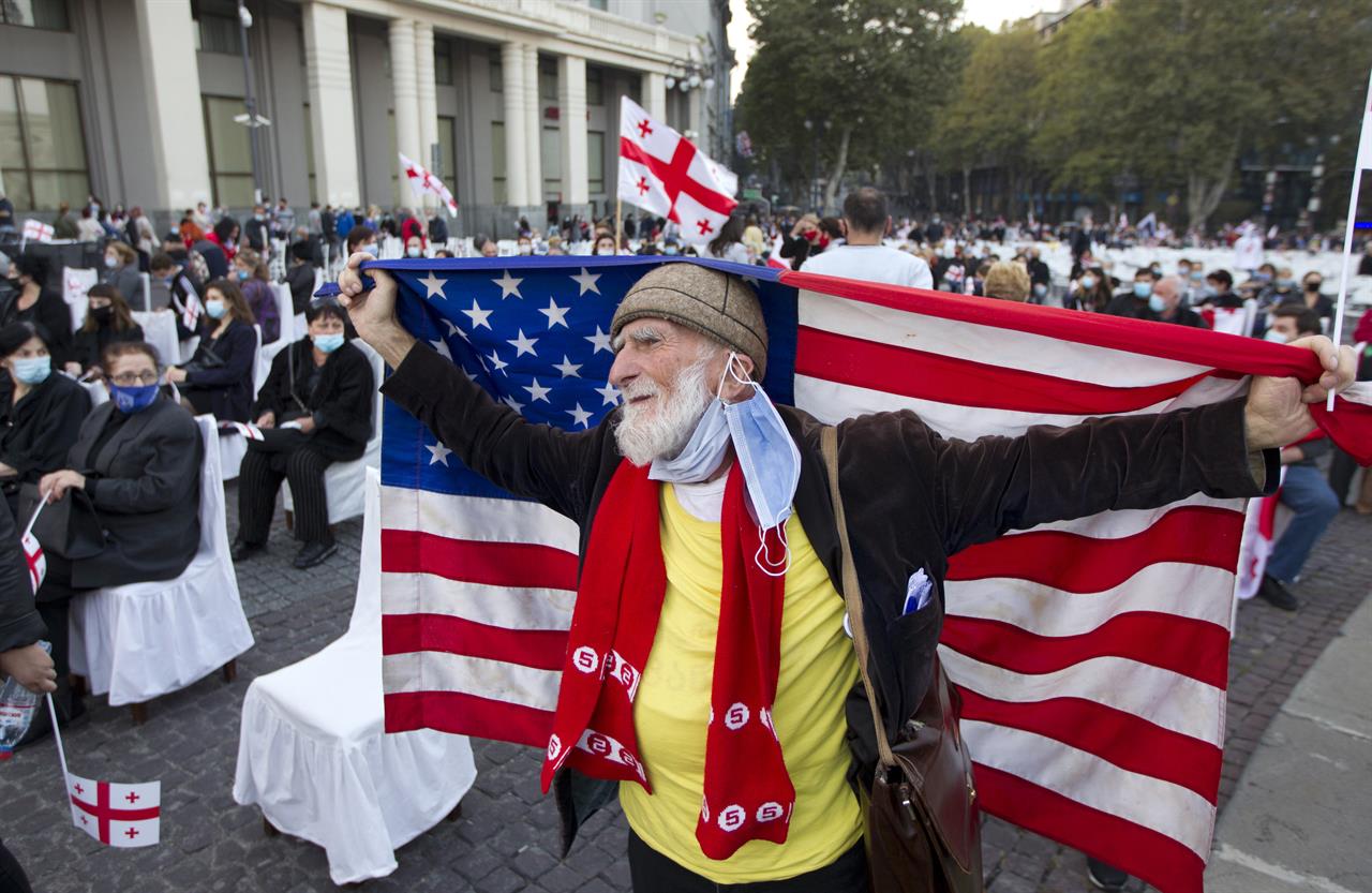 A supporters of the United National Movement party holds an American national flag as he attends a parliamentary election campaign rally in Tbilisi, Georgia, Thursday, Oct. 29, 2020. The parliamentary elections will take place in Georgia on Saturday, Oct. 31, 2020. (AP Photo/Shakh Aivazov)