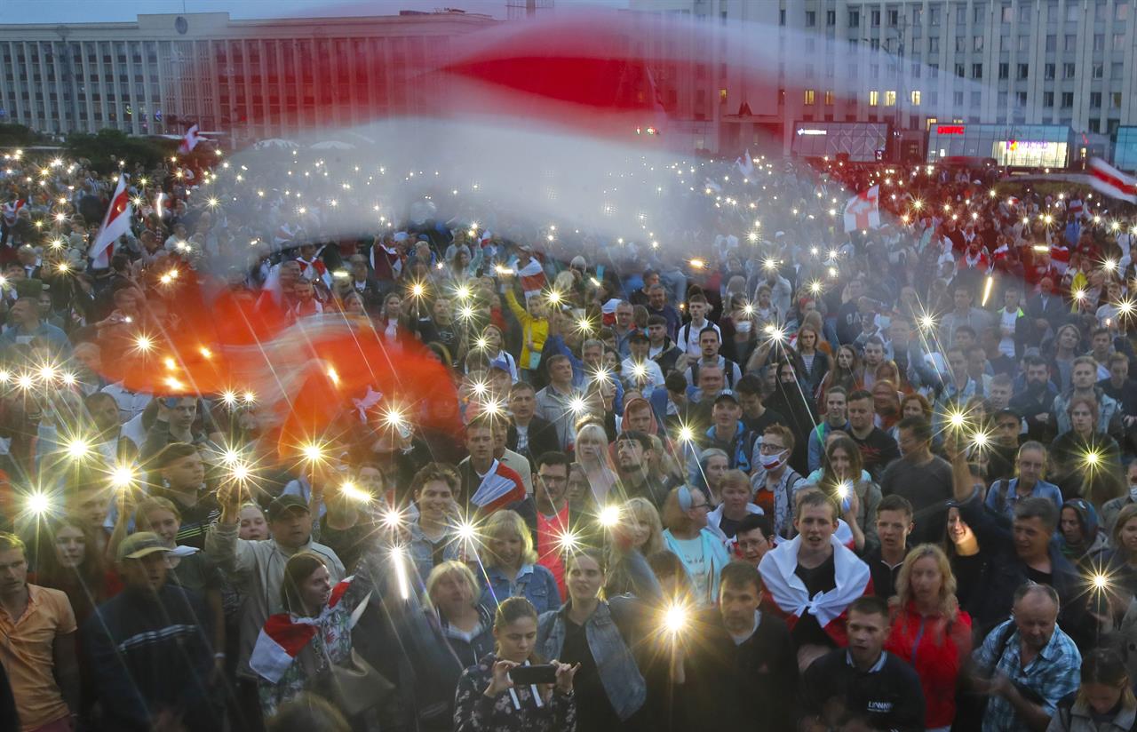 FILE - In this Wednesday, Aug. 19, 2020 file photo, Belarusian opposition supporters light phones lights and wave an old Belarusian national flags during a protest rally in front of the government building at Independent Square in Minsk, Belarus. Belarus President Alexander Lukashenko has relied on massive arrests and intimidation tactics to hold on to power despite nearly three months of protests sparked by his re-election to a sixth term, but continuing protests have cast an unprecedented challenge to his 26-year rule. (AP Photo/Dmitri Lovetsky, File)