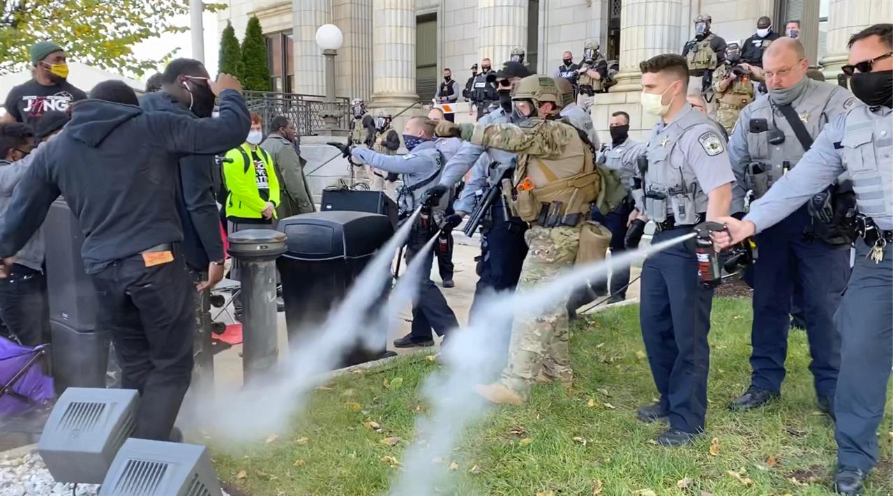 In this image taken from video, Alamance County sheriff's deputies use pepper spray on a crowd of protesters outside the courthouse in Graham, N.C., Saturday, Oct. 31, 2020. A get-out-the vote rally that ended with North Carolina police pepper spraying and arresting attendants was the result of participants blocking the roadway without authorization, authorities said Saturday. (Carli Brosseau/The News & Observer via AP)