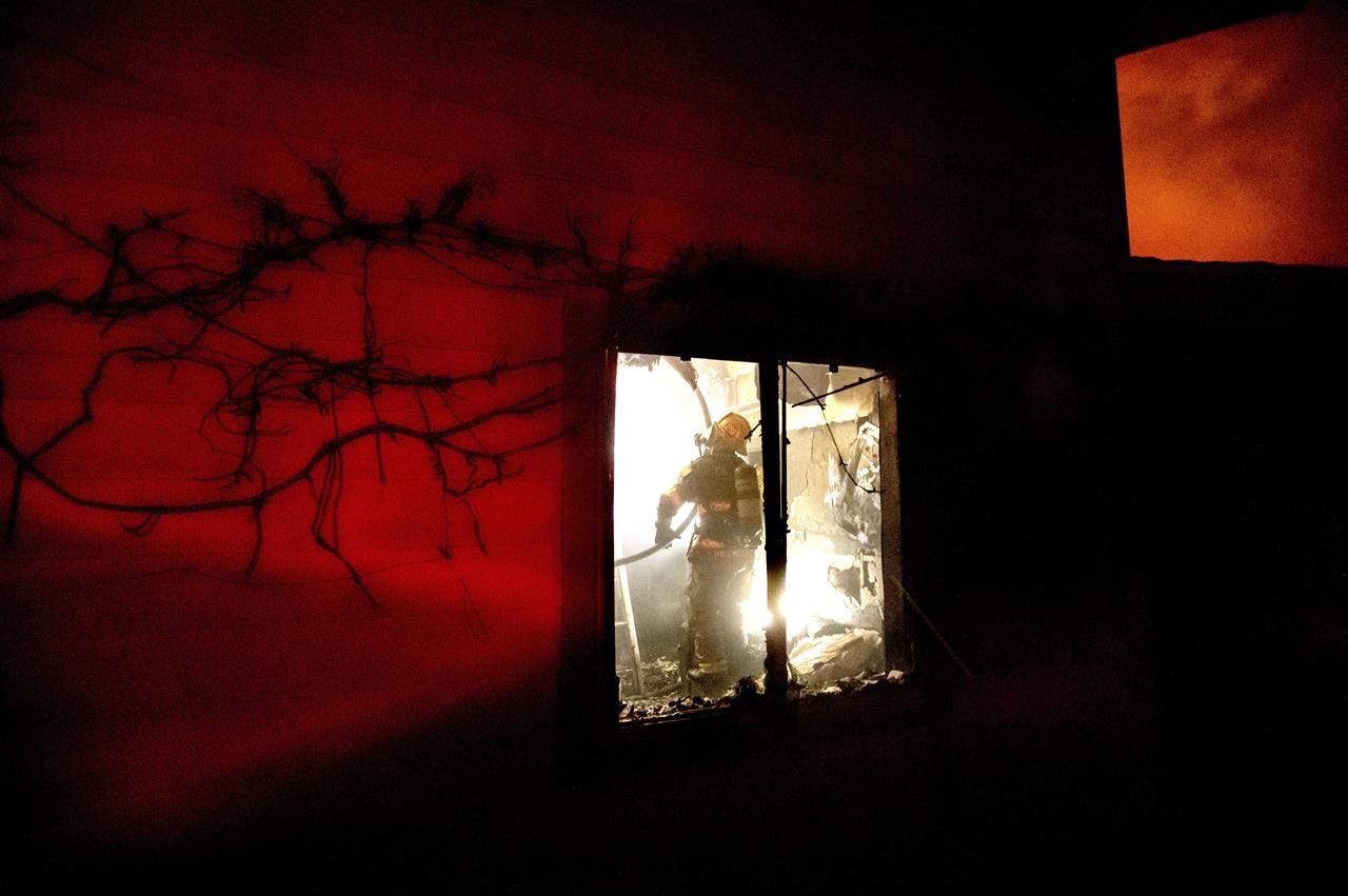 A firefighter extinguishes flames in a burning home as the Mountain View Fire tears through the Walker community in Mono County, Calif., on Wednesday, Nov. 18, 2020. (AP Photo/Noah Berger)