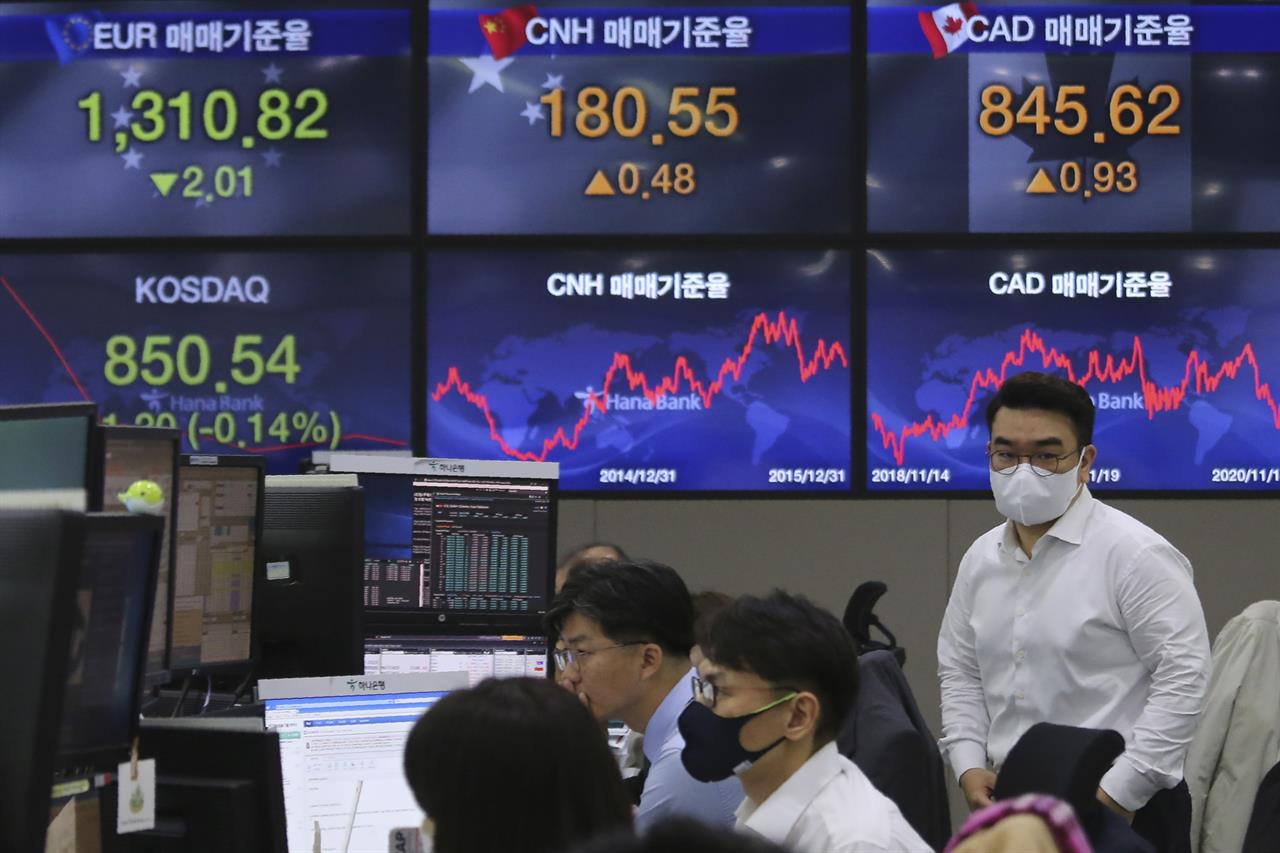 A currency trader passes by screens showing foreign exchange rates at the foreign exchange dealing room of the KEB Hana Bank headquarters in Seoul, South Korea, Thursday, Nov. 19, 2020. Asian stocks followed Wall Street lower on Thursday as anxiety about the economic fallout from rising coronavirus infections in the United States and Europe clashed with optimism about a possible vaccine. (AP Photo/Ahn Young-joon)