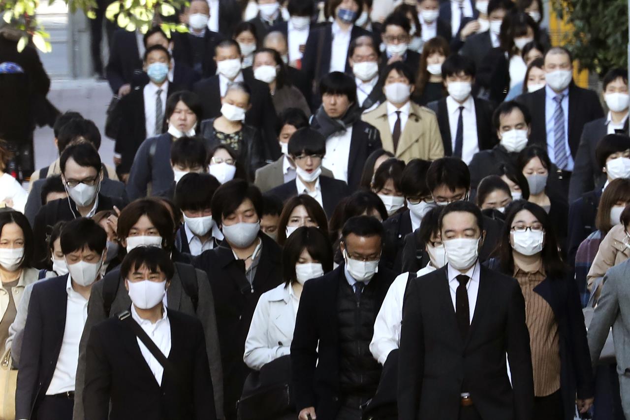 Commuters wearing face masks to protect against the spread of the coronavirus walk along a pedestrian sidewalk in Tokyo, Tuesday, Nov. 17, 2020. (AP Photo/Koji Sasahara)