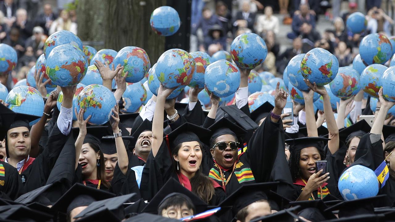 FILE— In this May 30, 2019 file photo, graduates of Harvard's John F. Kennedy School of Government hold aloft inflatable globes as they celebrate graduating during Harvard University's commencement exercises in Cambridge, Mass. A petition circulating at Harvard University demands that school officials create new accountability standards for former Trump administration officials who seek to work or speak on campus, an idea that has drawn outrage from prominent conservatives. (AP Photo/Steven Senne, File)