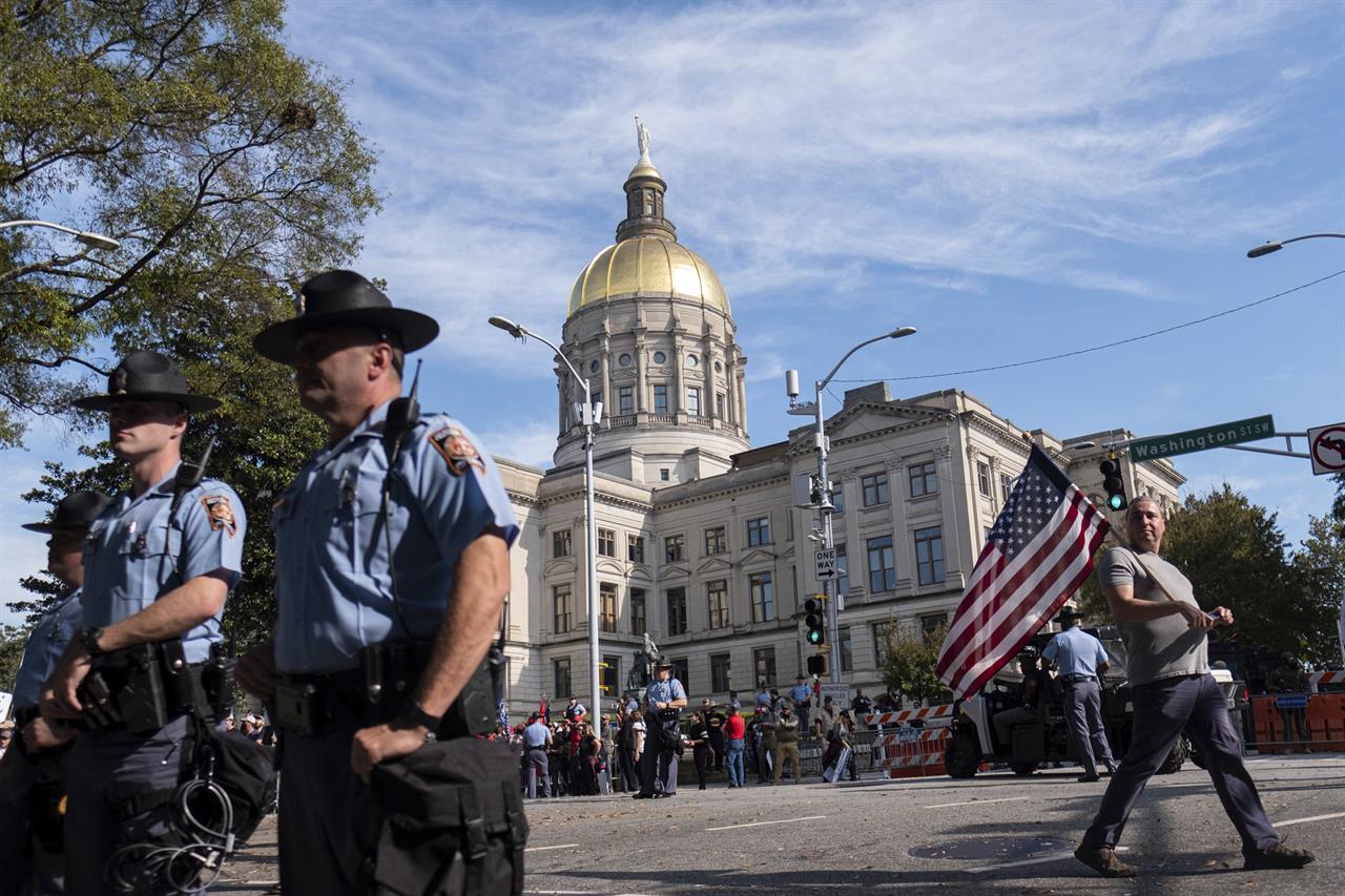 A man carrying an American flag leaves the rally for President Donald Trump outside of the Georgia State Capitol in Atlanta on Saturday, Nov. 21, 2020, and looks down the street at a group of counter protesters. (AP Photo/Ben Gray)
