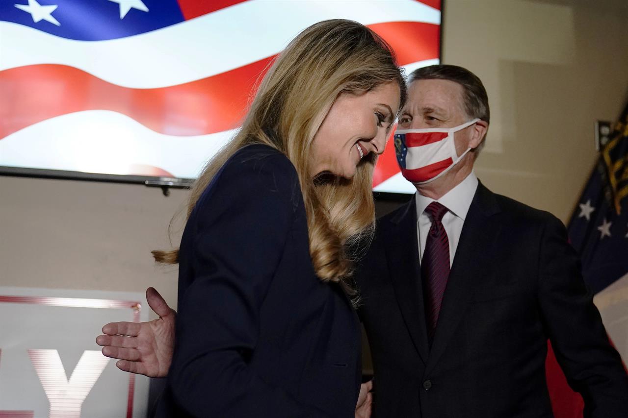 Republican candidates for U.S. Senate Sen. David Perdue leads Sen. Sen. Kelly Loeffler, off the stage during a campaign rally on Friday, Nov. 13, 2020, in Cumming, Ga. Perdue and Democratic candidate Jon Ossoff are in a runoff election for the Senate seat in Georgia. (AP Photo/Brynn Anderson)