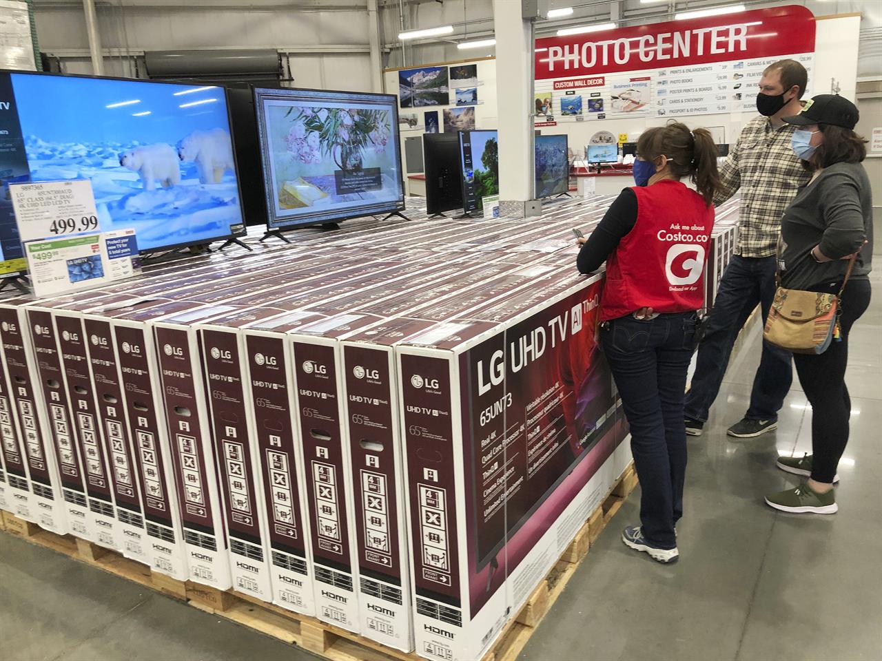 A sales associate helps customers as they consider the purchase of a big-screen television at a Costco warehouse on Wednesday, Nov. 18, 2020, in Sheridan, Colo. U.S. consumer confidence fell to a reading of 96.1 in November as rising coronavirus cases pushed Americans’ confidence down to the lowest level since August. The Conference Board said the November reading represented a drop from a revised 101.4 in October. (AP Photo/David Zalubowski)
