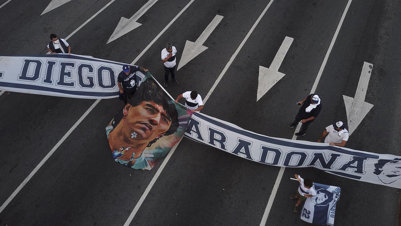 Soccer fans carry a banner of Diego Maradona in downtown Buenos Aires, Argentina, Wednesday, Nov. 25, 2020. Diego Maradona, the Argentine soccer great who was among the best players ever and who led his country to the 1986 World Cup title died from a heart attack at his home in Buenos Aires. He was 60. (AP Photo/Victor Caivano)