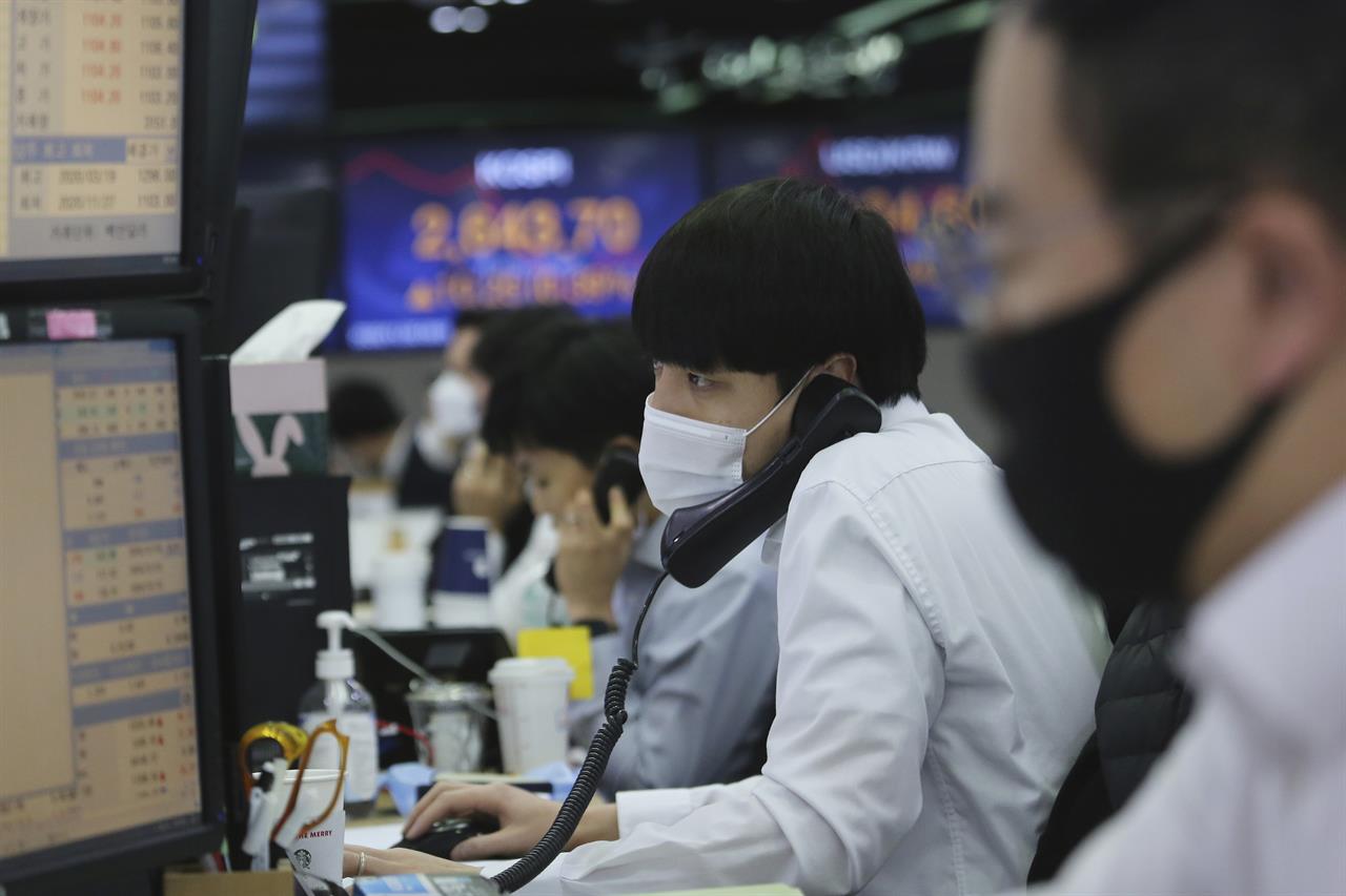 A currency trader watches monitors at the foreign exchange dealing room of the KEB Hana Bank headquarters in Seoul, South Korea, Monday, Nov. 30, 2020. Asian shares were mixed on Monday on renewed caution despite a record high finish on Wall Street last week driven by hopes for a COVID-19 vaccine and relief for the global economy. (AP Photo/Ahn Young-joon)