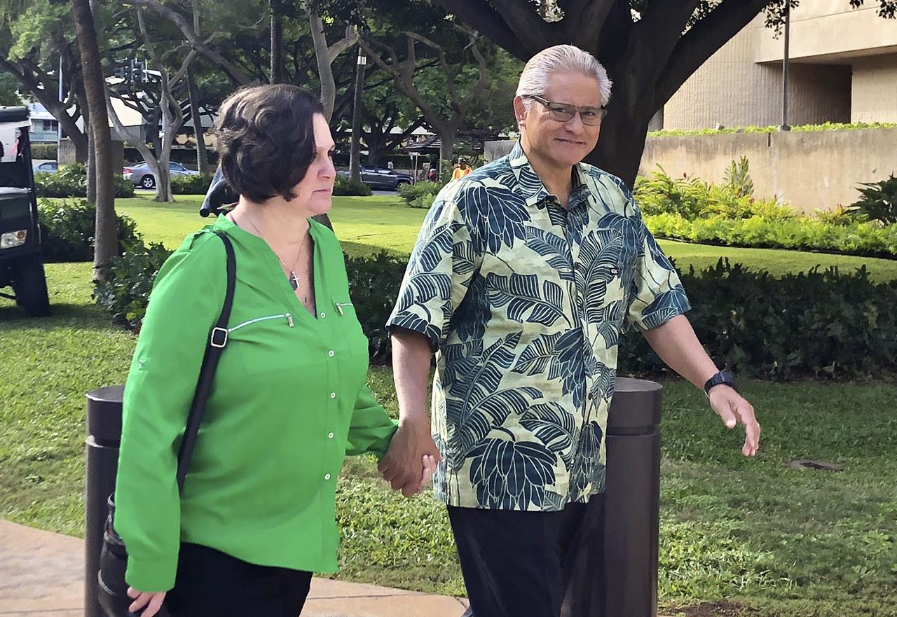 FILE - In this March 12, 2019, file photo, retired Honolulu police chief Louis Kealoha and his wife, former deputy city prosecutor Katherine Kealoha, hold hands while walking to U.S. district court in Honolulu. A once-respected, now-estranged power couple are scheduled to be sentenced Monday, Nov. 30, 2020, in Hawaii's biggest corruption case. A jury convicted Katherine and Louis Kealoha of conspiracy in a plot to frame her uncle to keep him from revealing fraud that financed their fancy lives. (AP Photo/Jennifer Sinco Kelleher, File)