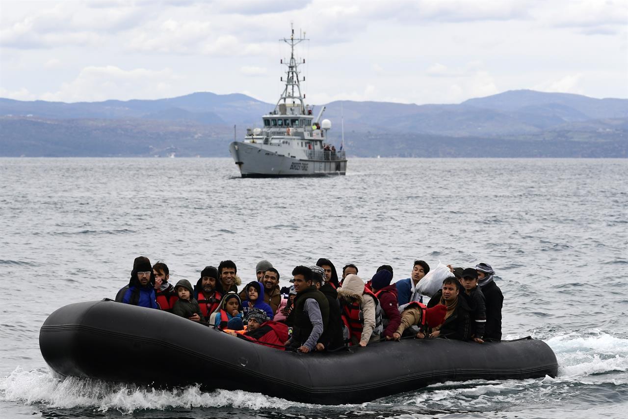 FILE - In this Friday, Feb. 28, 2020 file photo, migrants arrive with a dinghy accompanied by a Frontex vessel at the village of Skala Sikaminias, on the Greek island of Lesbos, after crossing the Aegean sea from Turkey. The head of the European Union's border and coast guard agency faces a grilling on Tuesday, Dec. 1, 2020 by EU lawmakers as pressure mounts over allegations that Frontex was involved in illegal pushbacks aimed at preventing migrants or refugees entering Europe through the Greek islands. (AP Photo/Michael Varaklas, File)