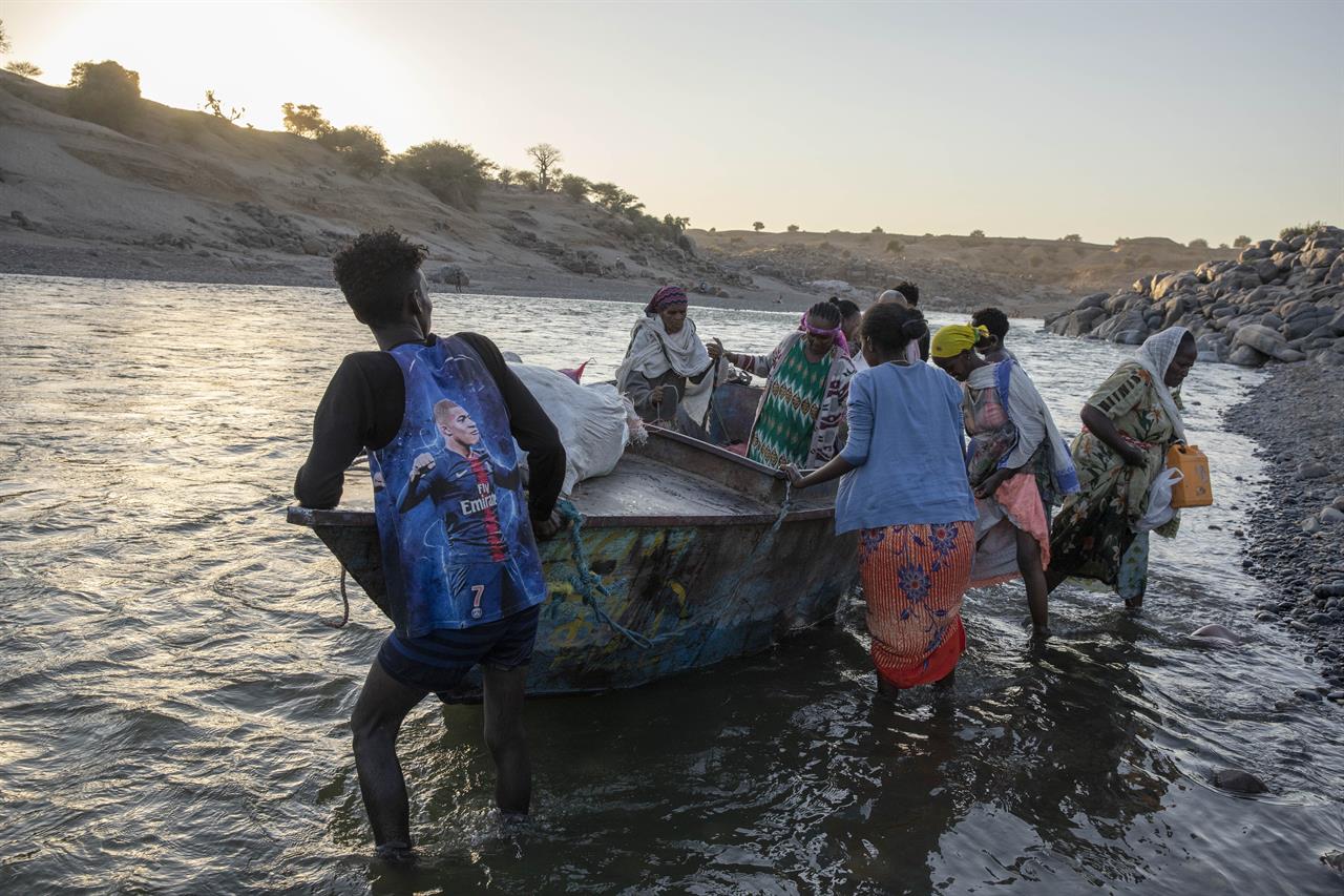 Tigray refugees arrive on the banks of the Tekeze River on the Sudan-Ethiopia border, in Hamdayet, eastern Sudan, Wednesday, Dec. 2, 2020. Ethiopian forces on Thursday, Dec. 3, 2020 blocked people from the country's embattled Tigray region from crossing into Sudan at the busiest crossing point for refugees, Sudanese forces said. (AP Photo/Nariman El-Mofty)