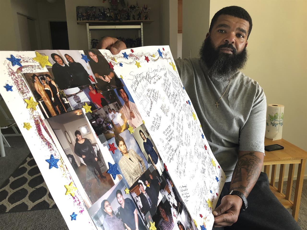 FILE - In this June 19, 2020, file photo, Roland Mack holds a poster with pictures and messages made by family members in memory of his sister, Chantee Mack, in District Heights, Md., The Prince George's County, Md., public health worker died of COVID-19 after, family and co-workers believe, she and several colleagues contracted the disease in their office. A Maryland health department is taking new steps to protect its workers six months after a COVID-19 outbreak killed a veteran employee who was twice denied permission to work from home. (AP Photo/Federica Narancio, File)