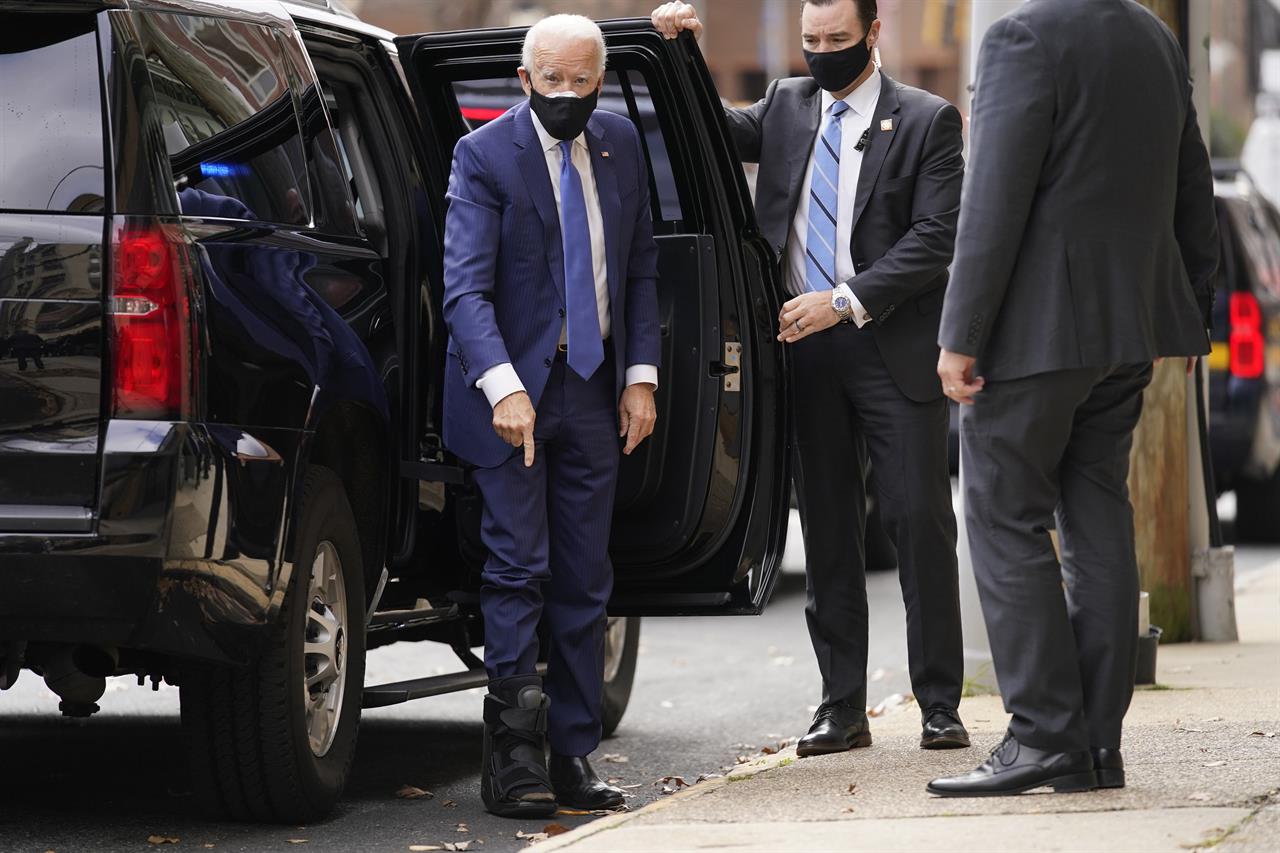 President-elect Joe Biden points to his medical boot as he arrives at The Queen theater, Tuesday, Dec. 1, 2020, in Wilmington, Del. (AP Photo/Andrew Harnik)