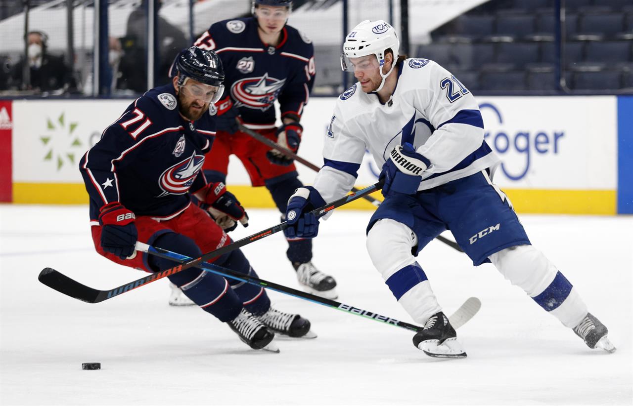 Tampa Bay Lightning forward Brayden Point, right, reaches for the puck in front of Columbus Blue Jackets forward Nick Foligno during the first period an NHL hockey game in Columbus, Ohio, Thursday, April 8, 2021. (AP Photo/Paul Vernon)