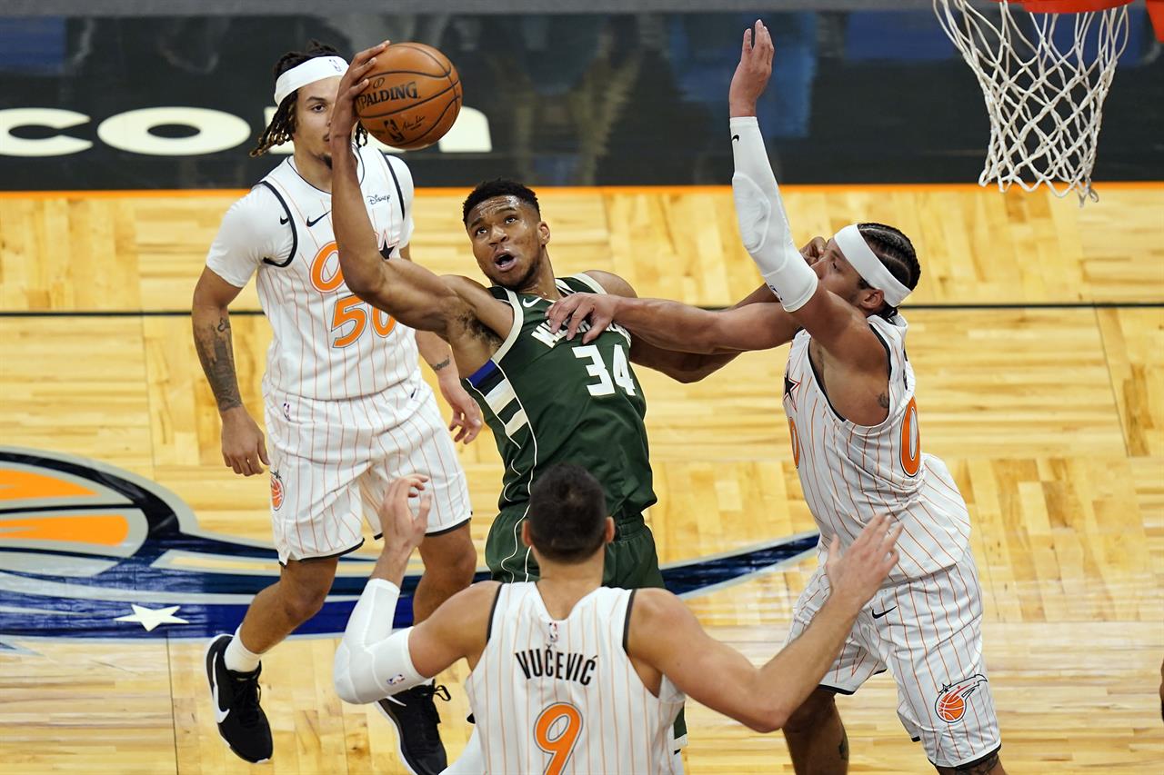 Milwaukee Bucks forward Giannis Antetokounmpo (34) tries to get control of a loose ball between Orlando Magic guard Cole Anthony, bak left, center Nikola Vucevic (9) and forward Aaron Gordon, right, during the second half of an NBA basketball game, Monday, Jan. 11, 2021, in Orlando, Fla. (AP Photo/John Raoux)