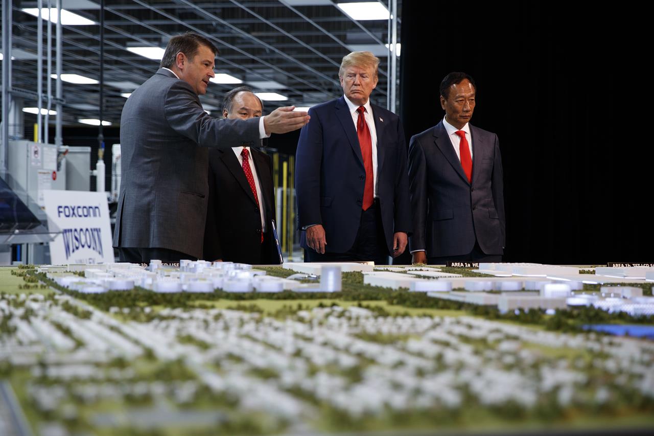 FILE - In this June 28, 2018 photo, President Donald Trump takes a tour of Foxconn with Foxconn chairman Terry Gou, right, and CEO of SoftBank Masayoshi Son in Mt. Pleasant, Wis. Foxconn Technology Group will qualify for up to $80 million in state tax incentives under a new contract agreed to on Tuesday, April 20, 2021 that downsizes the scale of credits as the size of the envisioned manufacturing facility has also shrunk. Gov. Tony Evers announced details of the new contract. (AP Photo/Evan Vucci, File)