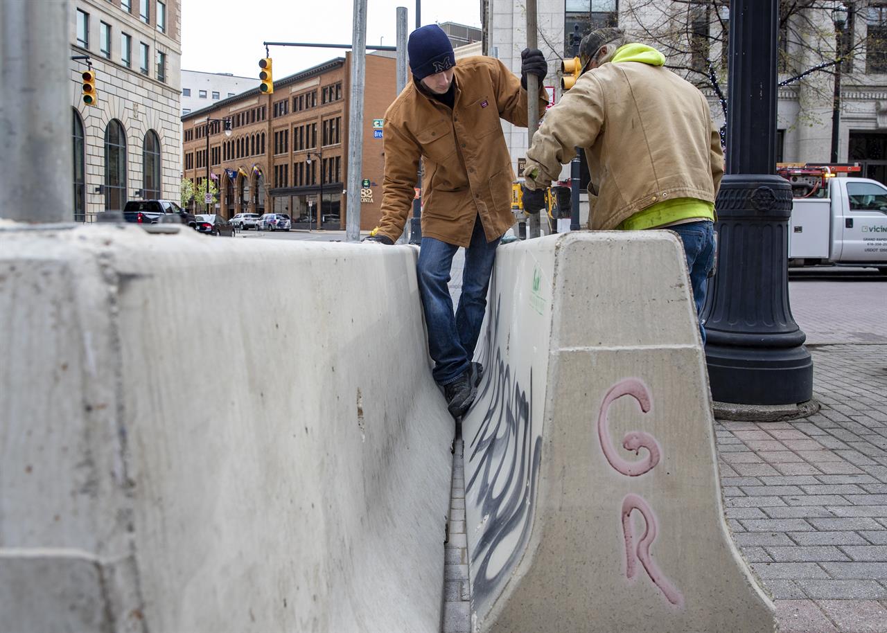 Cole Bond, left, and Mike Jack, from Fence Consultants of West Michigan, put up barricades in downtown Grand Rapids, Mich., Tuesday, April 20, 2021, as a jury deliberates fate of Derek Chauvin in death of George Floyd. Grand Rapids had some of Michigan's worst violence last May after the death of Floyd. (Cory Morse/MLive.com/The Grand Rapids Press via AP)