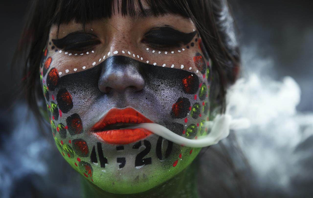 Ana Mendez Casteñeda smokes marijuana during "Fumaton 420" outside the national Senate in Mexico City, Tuesday, April 20, 2021. The demonstrators are calling for the legalization of marijuana. (AP Photo/Marco Ugarte)