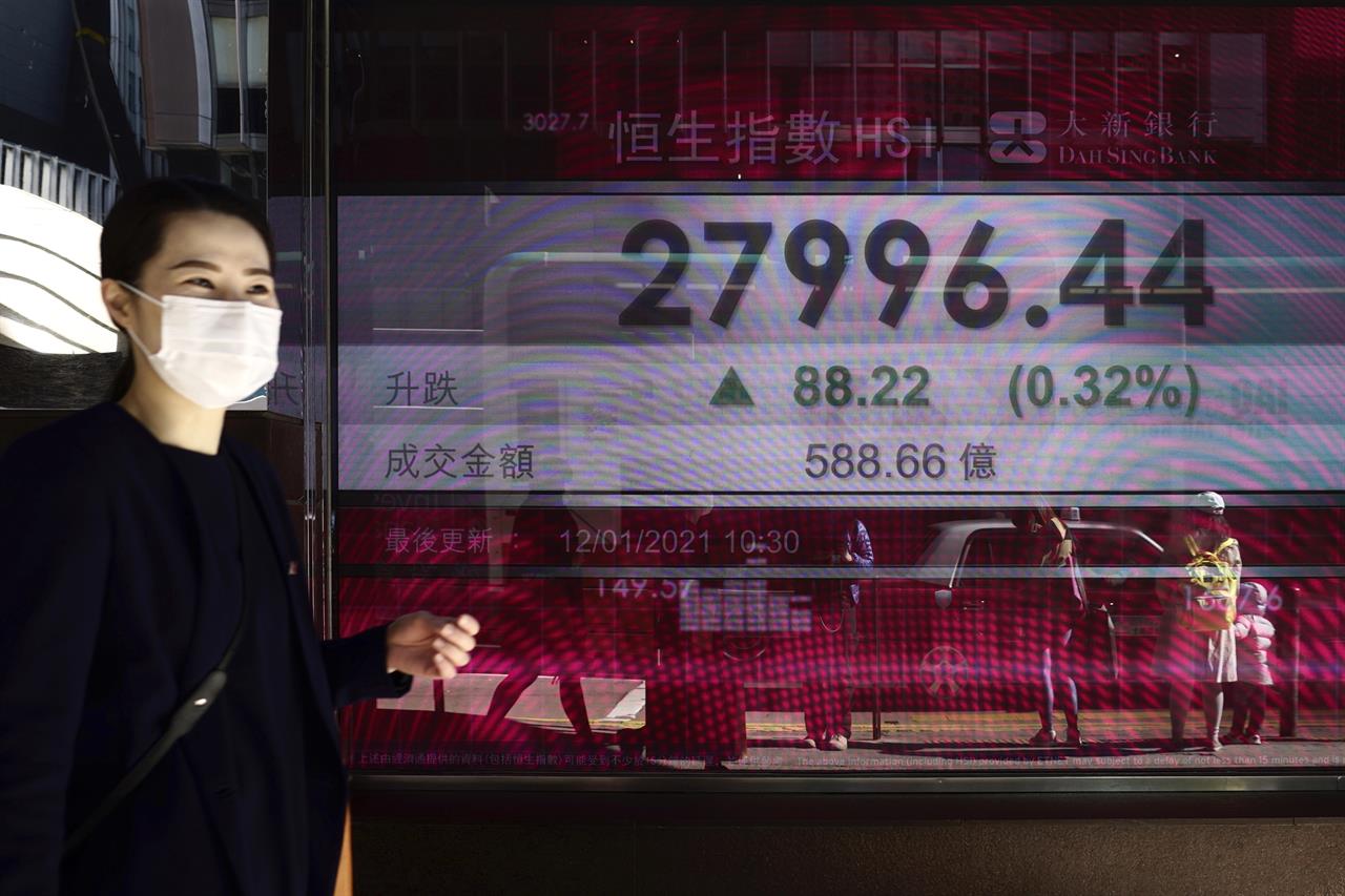 A woman walks past a bank's electronic board showing the Hong Kong share index at Hong Kong Stock Exchange in Hong Kong Tuesday, Jan. 12, 2021. Asian stocks advanced Tuesday as investors watched for details of U.S. President-elect Joe Biden's promised economic stimulus plan. (AP Photo/Vincent Yu)
