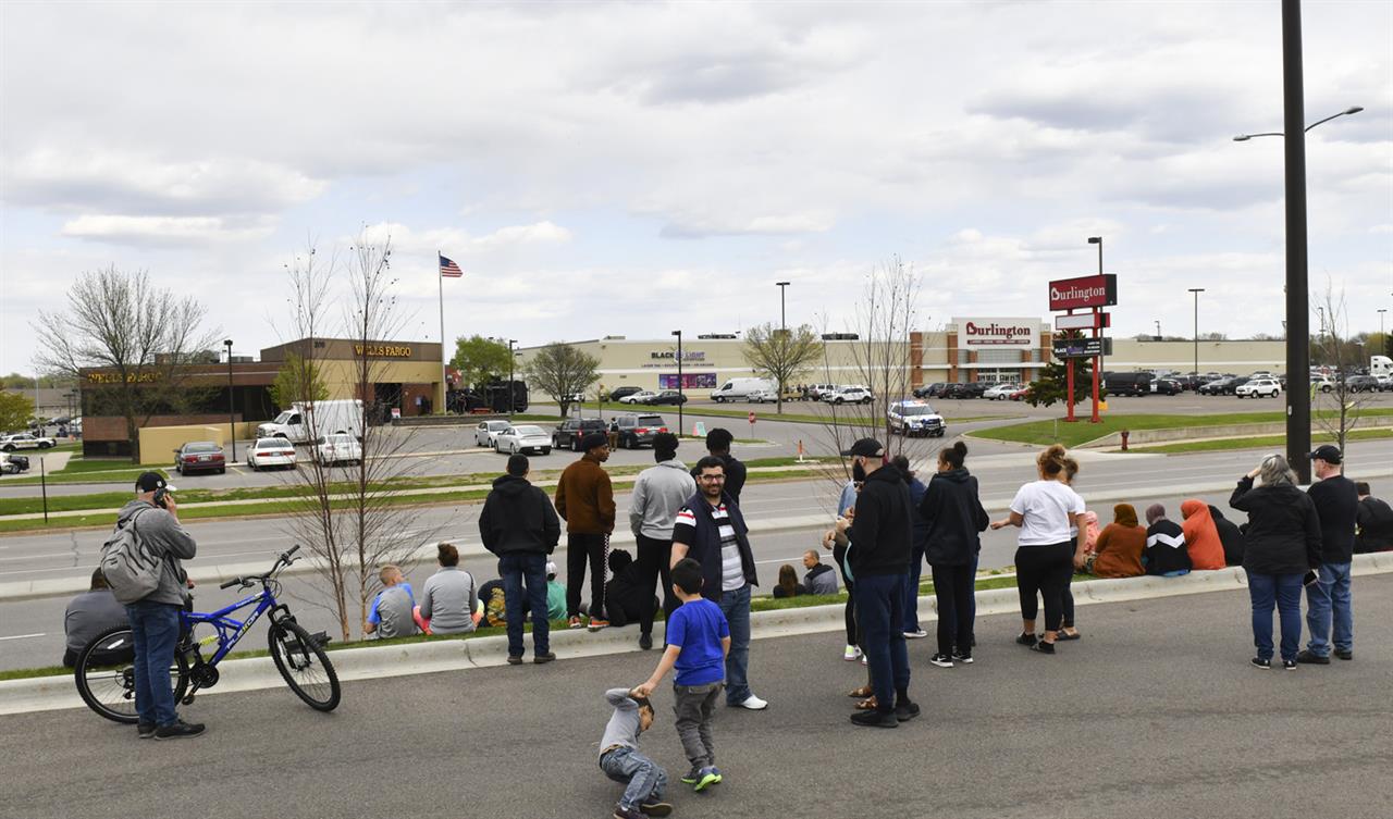 People gather in a nearby parking lot as officers surround the Wells Fargo branch Thursday May 6, 2021, in south St. Cloud, Minn. Police in Minnesota were on the scene Thursday of a reported bank robbery with hostages. (Dave Schwarz/St. Cloud Times via AP)