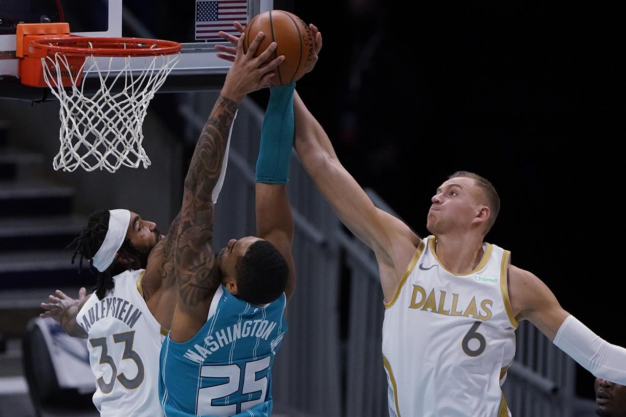 Dallas Mavericks' Kristaps Porzingis, right, blocks a shot by Charlotte Hornets forward P.J. Washington as center Willie Cauley-Stein defends during the second half of an NBA basketball game in Charlotte, N.C., Wednesday, Jan. 13, 2021. (AP Photo/Chris Carlson)