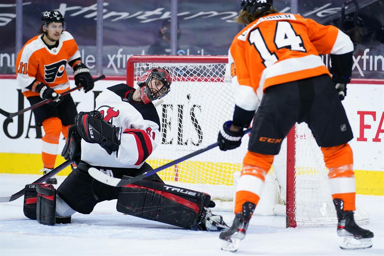 Philadelphia Flyers' Sean Couturier (14) scores a goal past New Jersey Devils' Scott Wedgewood (41) during the second period of an NHL hockey game, Monday, May 10, 2021, in Philadelphia. (AP Photo/Matt Slocum)