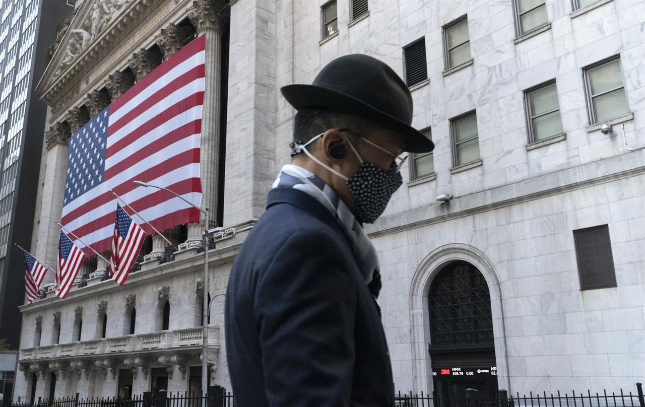 FILE - In this Nov. 16, 2020 file photo a man wearing a mask passes the New York Stock Exchange in New York. Stocks are opening lower on Wall Street again as Apple and other Big Tech companies give up more ground. The S&P 500 index fell 1.2% in the early going Tuesday, May 11, 2021. (AP Photo/Mark Lennihan, File)