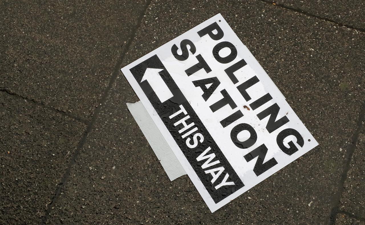 FILE - In this Thursday, Dec. 12, 2019 file photo, a polling station signpost lies on the pavement, in Twickenham, England. The British government announced Tuesday May 11, 2021, contentious plans to toughen election voting rules by requiring photo identification at polling stations, a move it says will protect the democratic system against electoral fraud. (AP Photo/Frank Augstein, File)