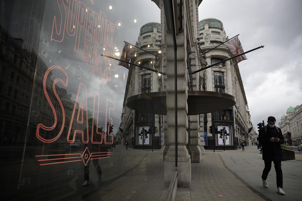 FILE - In this Friday, March 26, 2021 file photo, a person walks past a temporarily closed clothes shop on Regent Street in central London, where non-essential shops are closed during England's third coronavirus lockdown. The British economy contracted by 1.5% in the first quarter of 2021, a relatively modest contraction given that the country was in the midst of a strict lockdown to combat a second wave of the coronavirus. The Office for National Statistics also said Wednesday May 12, 2021, that the economy even managed to grow by 2.1% in March when the country began easing some restrictions. (AP Photo/Matt Dunham, File)