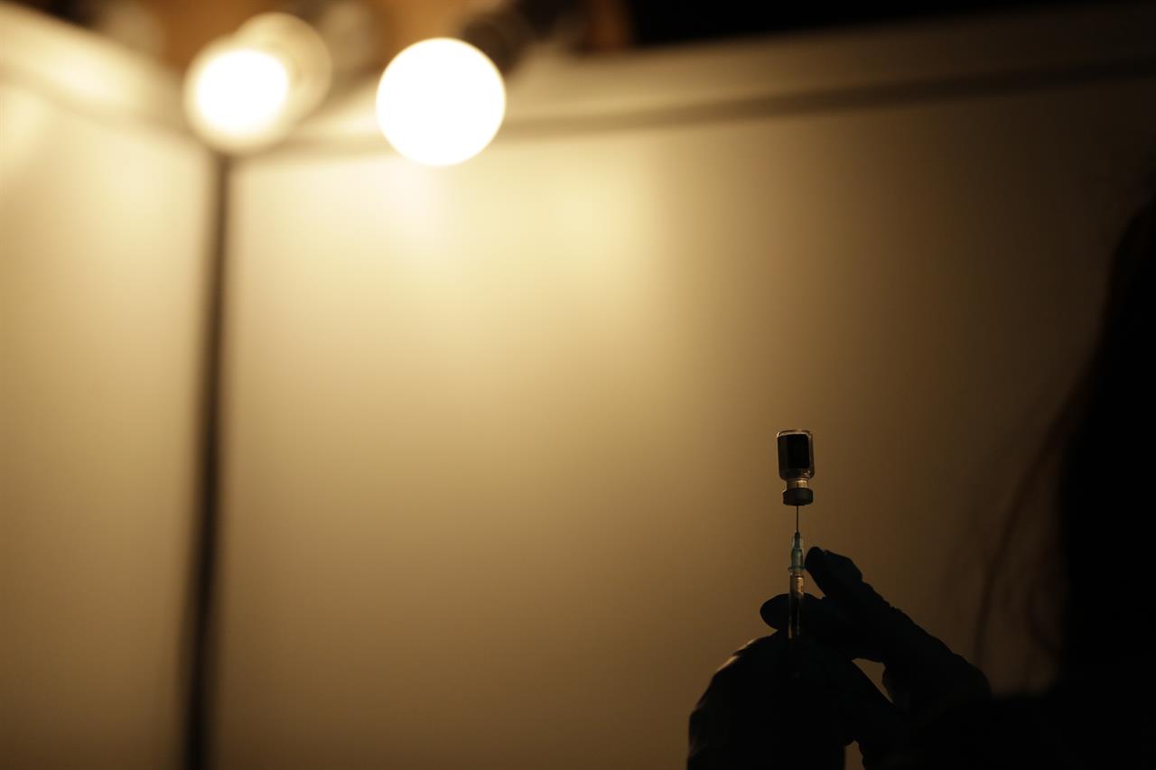 A volunteer vaccinator prepares to administer a dose of the Pfizer coronavirus vaccine at a vaccine centre in the Swaminarayan School in Neasden, north London, Saturday, May 1, 2021. (AP Photo/Matt Dunham)